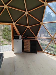 a kitchen in a timber frame tent with a refrigerator at Camping le Colorado in Rustrel