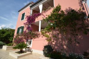 un edificio rosa con flores a un lado. en Villa Katarina Mali Lošinj en Mali Lošinj
