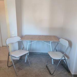 a table and two chairs sitting next to a wall at Pefki Apartment 8 in Artemísion