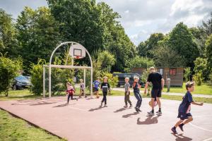 a group of children playing basketball on a basketball hoop at Huttopia Calvados - Normandie in Moyaux