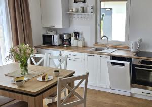 a kitchen with white cabinets and a wooden table at Pod kamieniem in Trzebiel