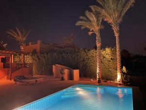 a swimming pool with palm trees and a building at Charming Lagoon Villa with pool Egyptian Style -Sabina 117 in Hurghada