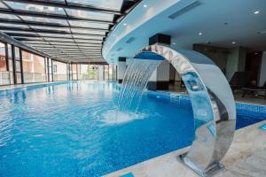 a pool with a water fountain in a building at Apart Hotel NAVI in Batumi