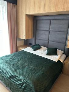 ein Schlafzimmer mit einem großen Bett mit einer grünen Bettdecke in der Unterkunft Lazurowy Apartament in Łeba