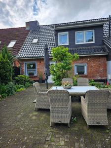 a table with chairs and an umbrella in front of a house at Ferienwohnung 2 Am Park in Divitz