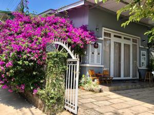 大叻Bắp's House Đà Lạt的一栋房子前面有一扇白色的大门，上面开着紫色的花