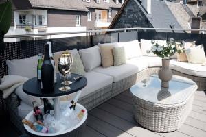 LUXXLOFT Luxusapartments Wetzlar في فيتسلار: أريكة بيضاء على شرفة مع طاولة مع كأس من النبيذ