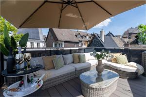 eine Terrasse mit einem weißen Sofa und einem Sonnenschirm in der Unterkunft LUXXLOFT Luxusapartments Wetzlar in Wetzlar