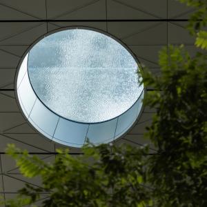 um espelho redondo pendurado no teto de um prédio em The Singapore EDITION em Singapura