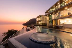 a building with a swimming pool next to the ocean at Villa W Luxury in Nai Harn Beach