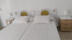 a large white bed with two pillows and a night stand at Divertida y Romántica in Pegalajar