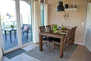 comedor con mesa y sillas y balcón en Ferienhaus "Deichglück" direkt an der Nordsee 2023 saniert, en Wesselburenerkoog