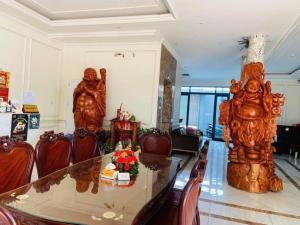 a dining room with a glass table and two statues at HOANG TRIEU-MARINA Thu Dau Mot in Ấp Phú Thọ