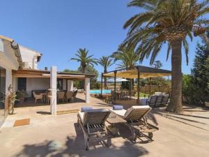 a patio with chairs and a pool and palm trees at Ca sa Padrina in Colonia Sant Jordi