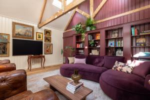 sala de estar con muebles de color púrpura y TV de pantalla plana. en Luxurious Harbour Loft d'Ouwe Moer en Róterdam