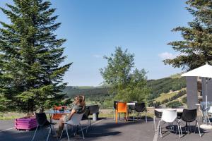 une femme assise à une table avec des chaises dans l'établissement Belambra Clubs Superbesse - Le Chambourguet, à Super-Besse