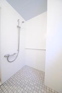y baño blanco con ducha y suelo de baldosa. en Residence Hotel Kamoike, en Kagoshima