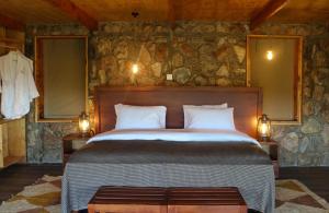 Alama Camp Mara في Ololaimutiek: غرفة نوم بسرير كبير في جدار حجري