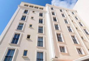 a tall white building with windows at B&B HOTEL Antibes Juan-les-Pins in Juan-les-Pins