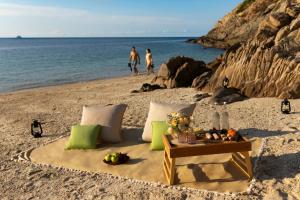 a table and pillows on a beach with the ocean at Six Senses Con Dao - Turtle Island Paradise in Con Dao
