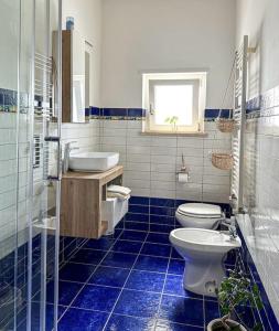 Un baño con azulejos azules, inodoro y lavabo. en Bilocale Brezza Marina, en Fiumicino 22 fotos más