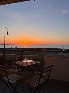 una mesa y sillas en un balcón con vistas a la puesta de sol en Bilocale Brezza Marina, en Fiumicino