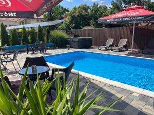 a swimming pool with chairs and a table and an umbrella at Brill Hotel Békéscsaba in Békéscsaba