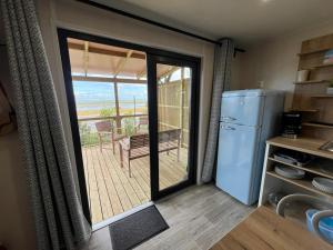 a kitchen with a refrigerator and a sliding glass door at Camping Ostréa **** in Dolus d'Oléron