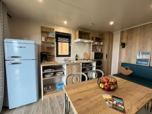 a kitchen with a white refrigerator and a table at Camping Ostréa **** in Dolus d'Oléron