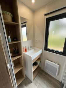 ein Bad mit einem weißen Waschbecken und einem Fenster in der Unterkunft Camping Ostréa **** in Dolus d'Oléron