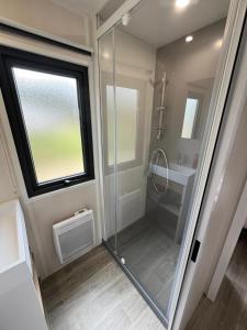 La salle de bains est pourvue d'une douche et d'une cabine de douche en verre. dans l'établissement Camping Ostréa ****, à Dolus-d'Oléron