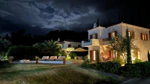 a large white house at night with a dark sky at Villa Serendipity Sea View in Porto Heli