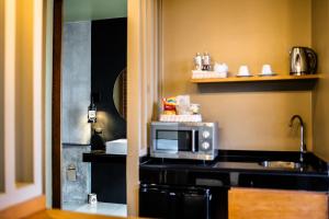 a kitchen with a microwave on top of a counter at The Mangrove by Blu Monkey Phuket in Panwa Beach
