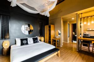 a bedroom with a large bed and a desk at The Mangrove by Blu Monkey Phuket in Panwa Beach