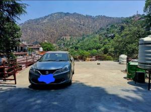 a car parked in a parking lot in front of a mountain at Pathgami homestay kainchi dhaam in Bhowāli