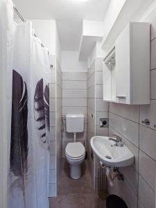 a white bathroom with a toilet and a sink at Marigold in Rijeka