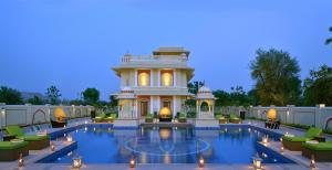 a large house with a pool in front of it at Indana Palace Jaipur in Jaipur