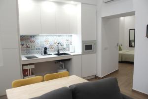 a kitchen with white cabinets and a table and chairs at Torre Solana 41 in Cádiz