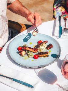 a person eating food on a plate on a table at Hôtel La Mandarine in Saint-Tropez
