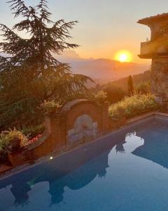 une piscine avec un coucher de soleil en arrière-plan dans l'établissement Wonderful Serena, à Coreglia Antelminelli