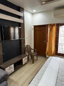 Zimmer mit einem TV, einem Stuhl und einem Sofa in der Unterkunft Temple View Home Stay in Tiruvannāmalai