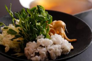 a black plate of food with broccoli and cauliflower at Arima Hot Spring Ryokan Hanamusubi in Kobe