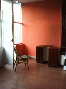 einen Stuhl in einem Zimmer mit orangefarbener Wand in der Unterkunft Frank Sinatra Apartment in Athen