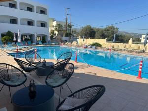a swimming pool with chairs and a table at Adele Resort in Adelianos Kampos