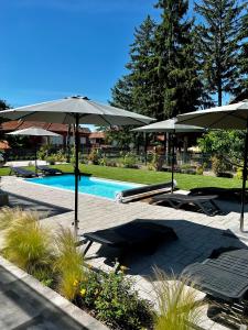 a swimming pool with umbrellas and chairs and a swimming pool at Best Apartman Boglár in Balatonboglár