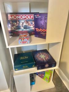 a book shelf filled with games and boardgames at The Capstone Retreat - Beautiful Detached Family Home By Coastline Retreats, Arcade Machine, Parking, BBQ in Bournemouth +19 photos