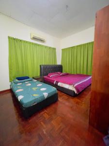 2 camas en una habitación con cortinas verdes en MY VILLA PD, en Port Dickson