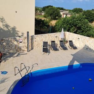 un grupo de sillas sentadas junto a una piscina en Iva apartman sa bazenom en Donji Zemunik