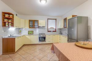 una cucina con armadi bianchi e frigorifero in acciaio inossidabile di Vineyard Homestead Vrtin - Happy Rentals a Dragatuš