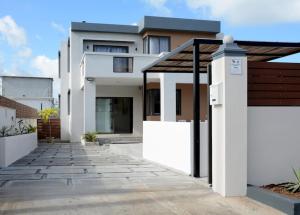 a white house with a walkway in front of it at Casa Blue Print Mahebourg in Mahébourg